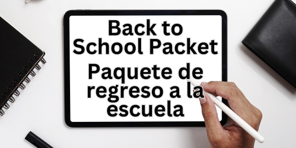 A tablet lies on a white surface, displaying bilingual text: 'Back to School Packet' in English and 'Paquete de regreso a la escuela' in Spanish. A hand holding a stylus is positioned near the screen, suggesting interaction. To the left of the tablet is a black notebook and pen, and to the right is another dark-colored object.